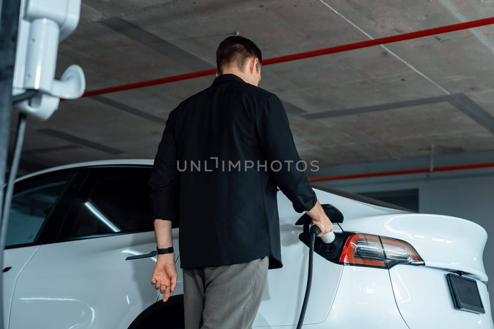 Young man travel with EV electric car to shopping center parking lot innards by biancoblue