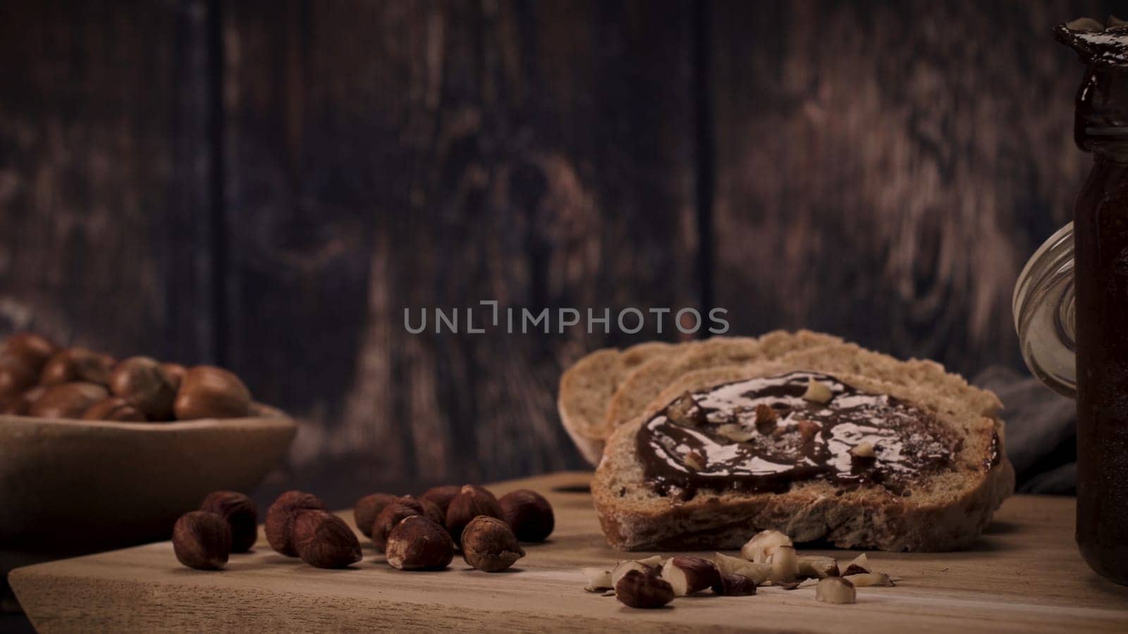 Vegan chocolate spread made of organic almond butter and organic cacao and honey, on dark rustic kitchen counter top.