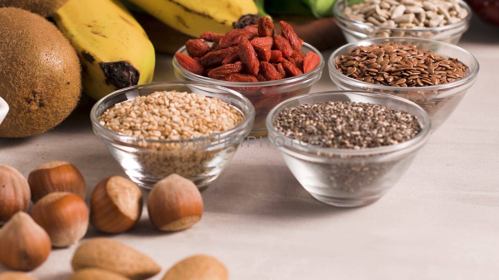 Superfoods on a gray background with copy space. Nuts, beans, greens and seeds. Healthy vegan food.