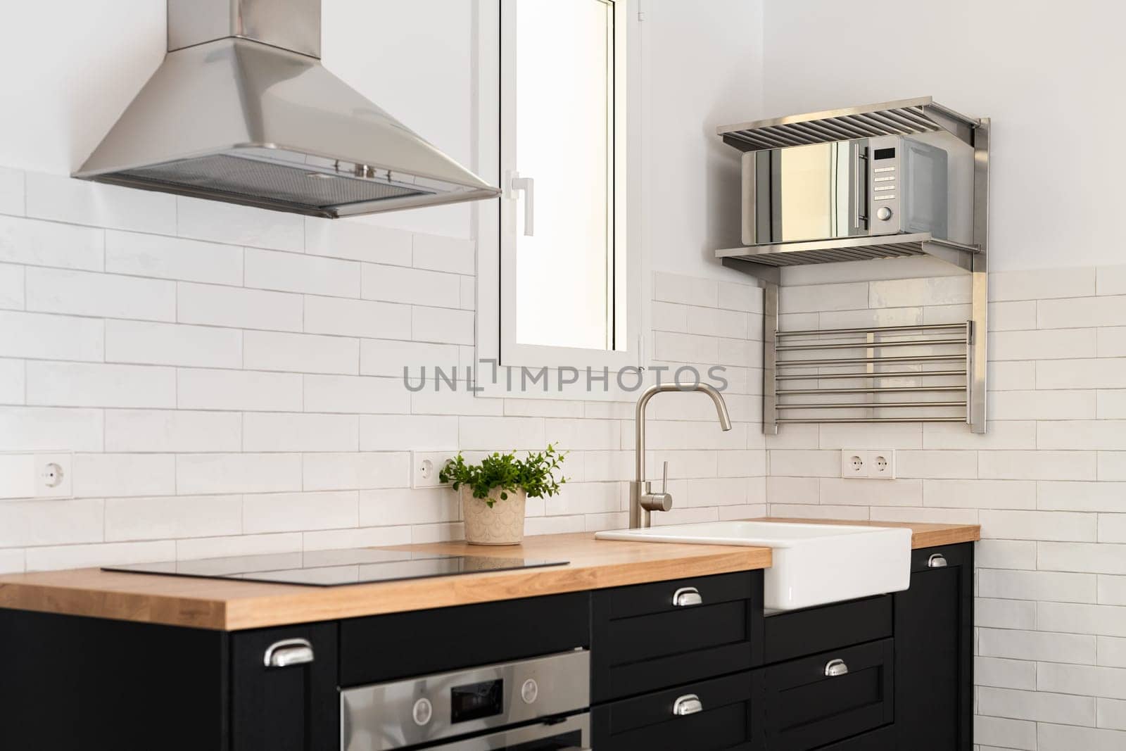 Modern devices for food preparation and sink in stylish kitchen. Renovated cooking area design with furniture and appliances in apartment