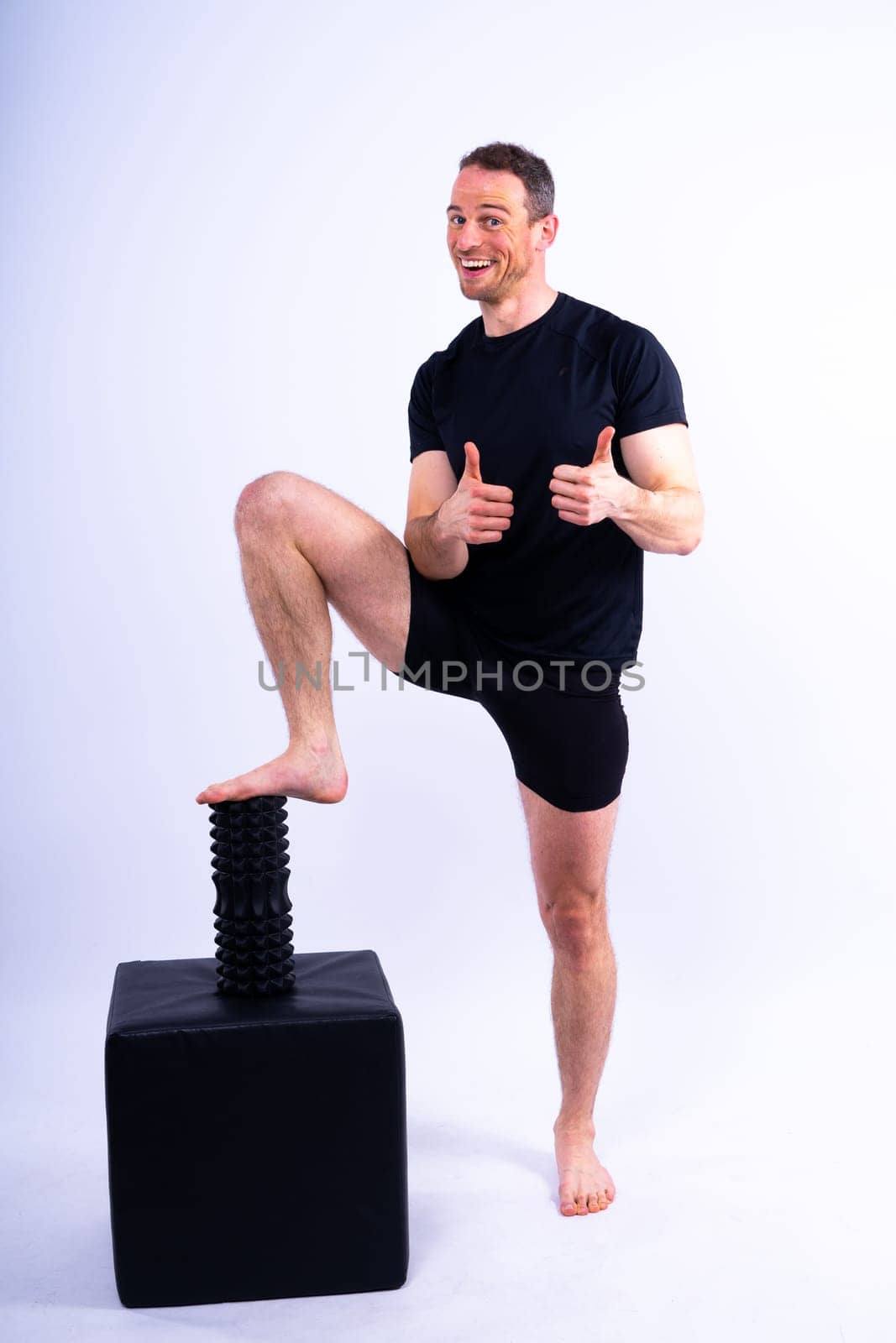 Athletic man using a foam roller to relieve sore muscles after a workout. by Zelenin