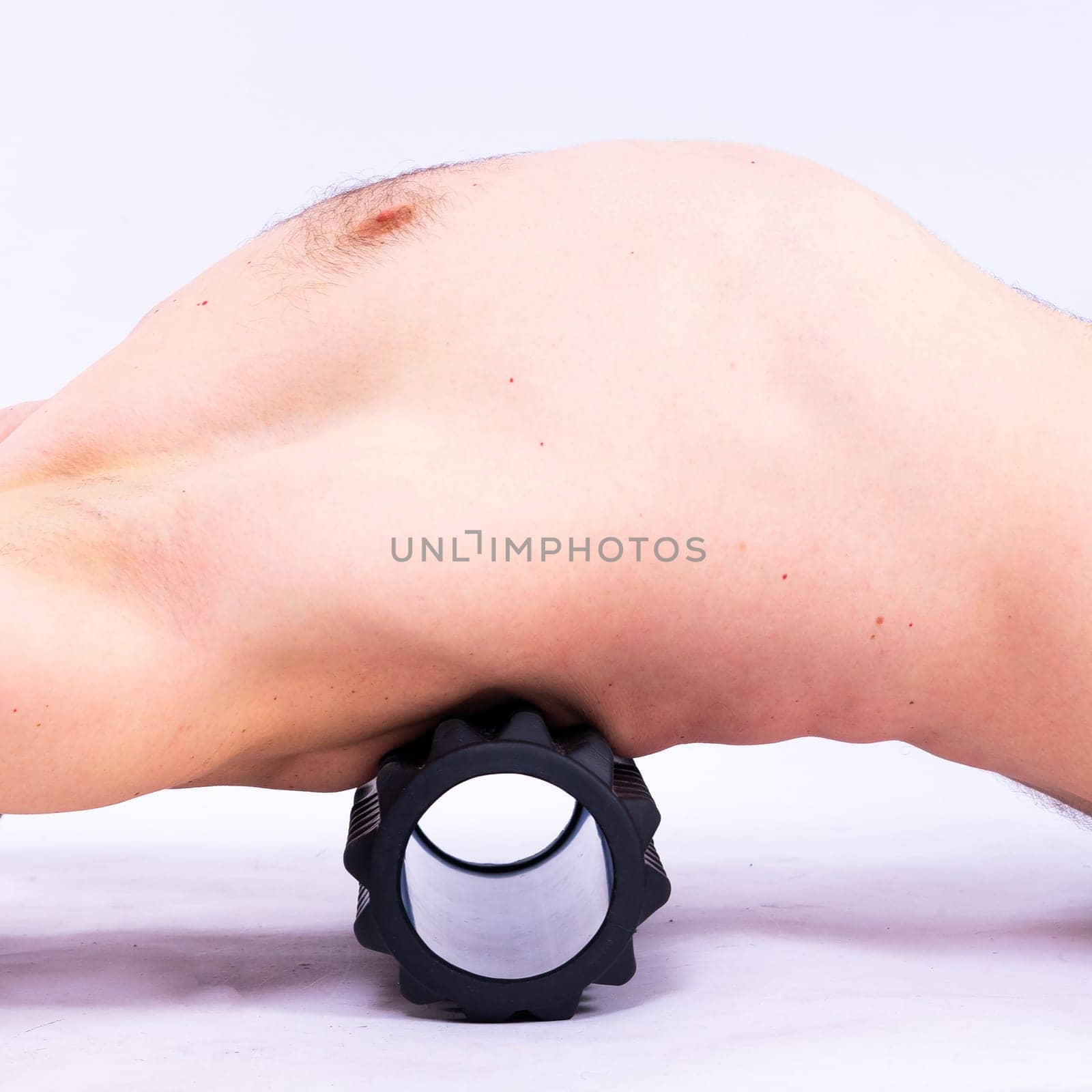 Athletic man using a foam roller to relieve sore muscles after a workout. by Zelenin