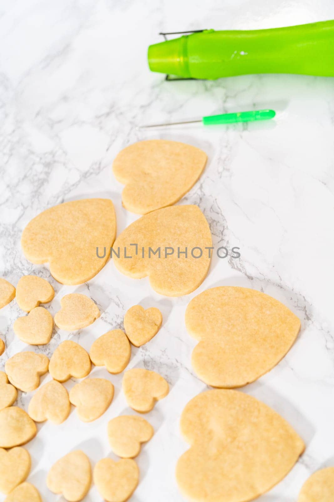 Decorating heart-shaped sugar cookies with pink and white royal icing for Valentine's Day.