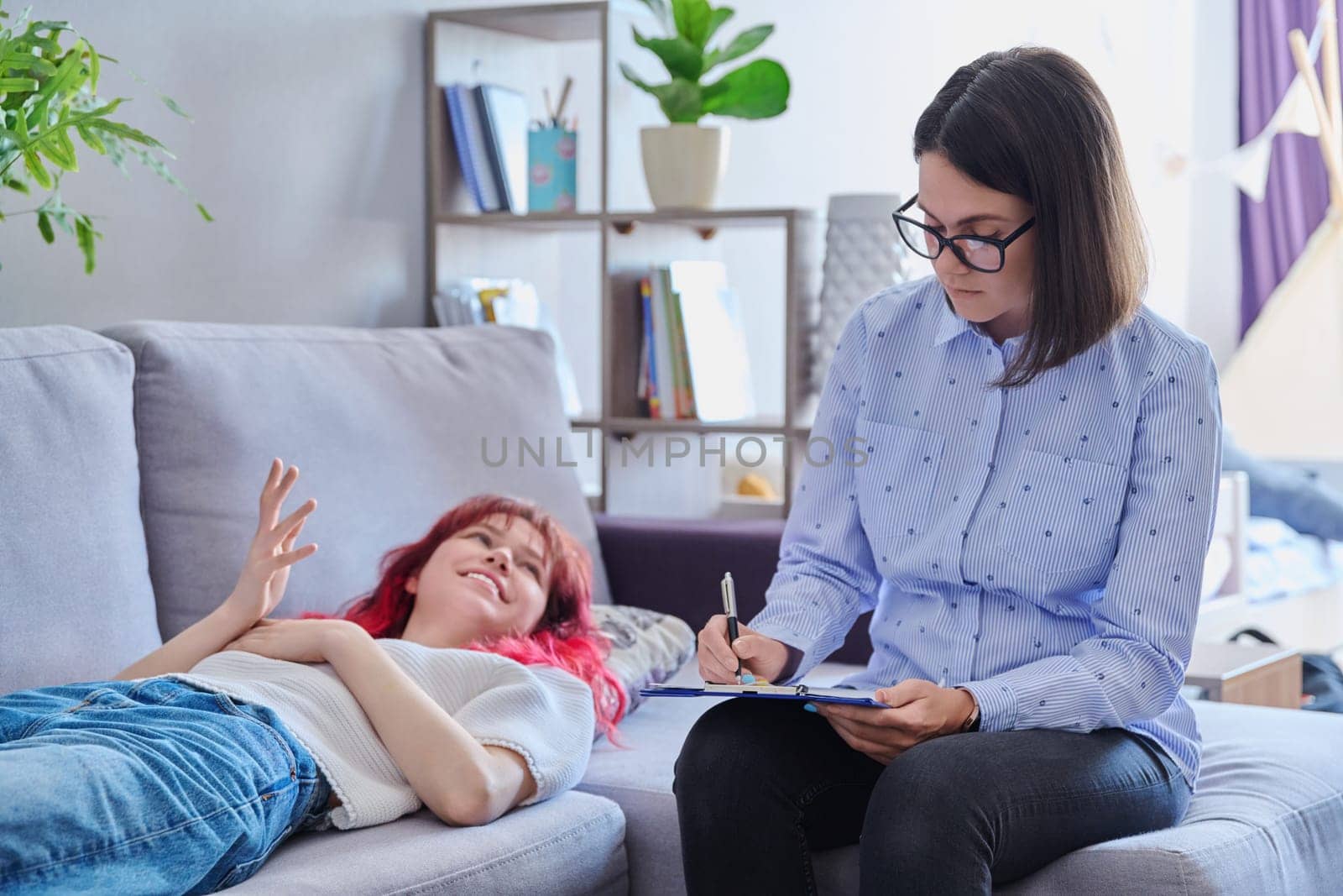 Psychologist helping teenage female, individual therapy in doctors office. Professional counselor listening teenager, girl lying on couch. Mental health, adolescence, psychology, psychiatry concept