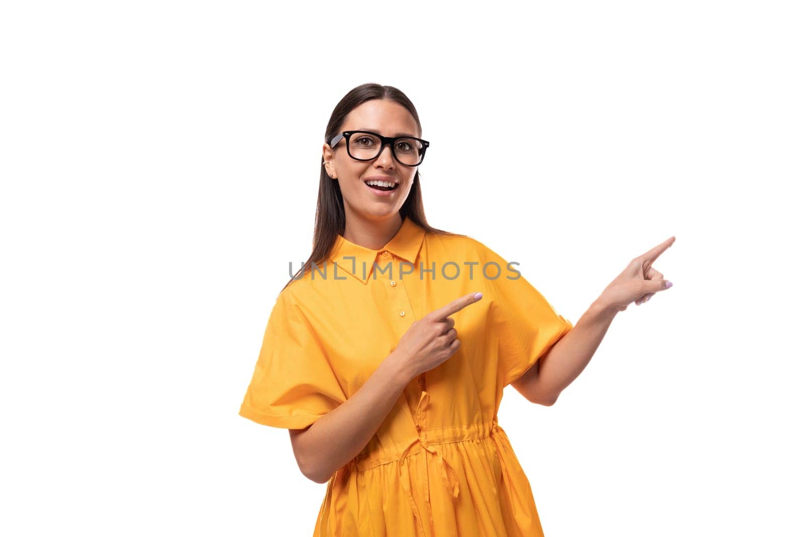 a young friendly black-haired woman with glasses dressed in an orange summer dress shows her hand to the side by TRMK