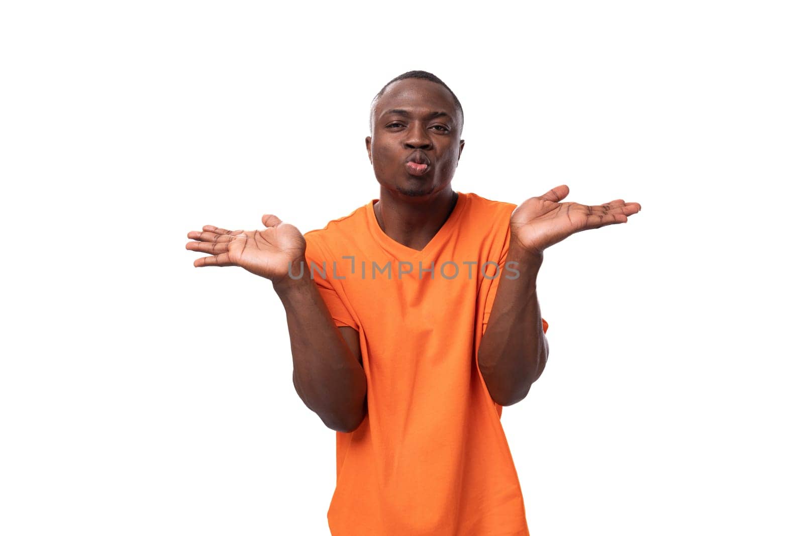 a young handsome American man dressed in an orange t-shirt is having doubts. corporate clothing concept.