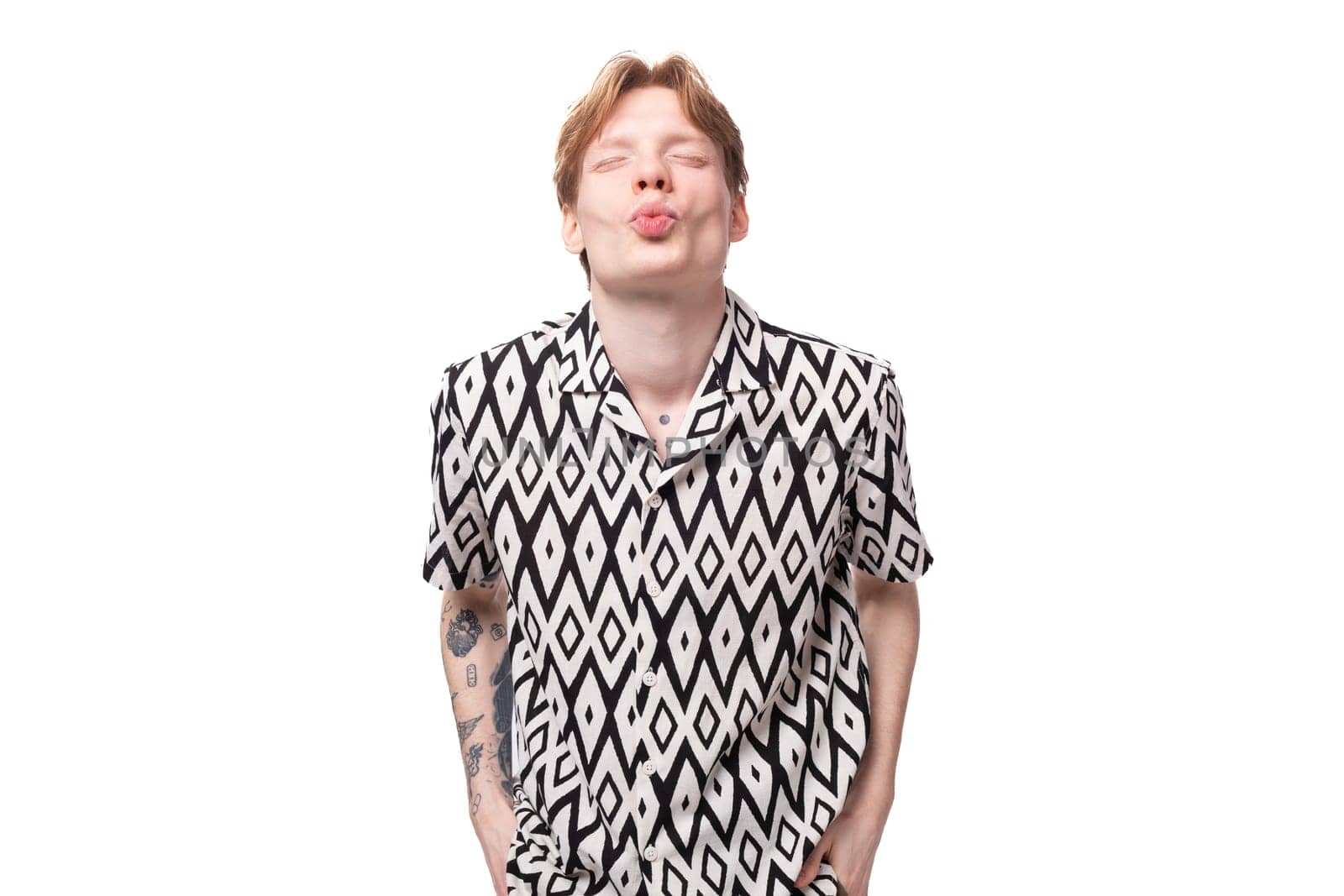 young caucasian man in love with reddish golden hair in a summer shirt sends an air kiss by TRMK