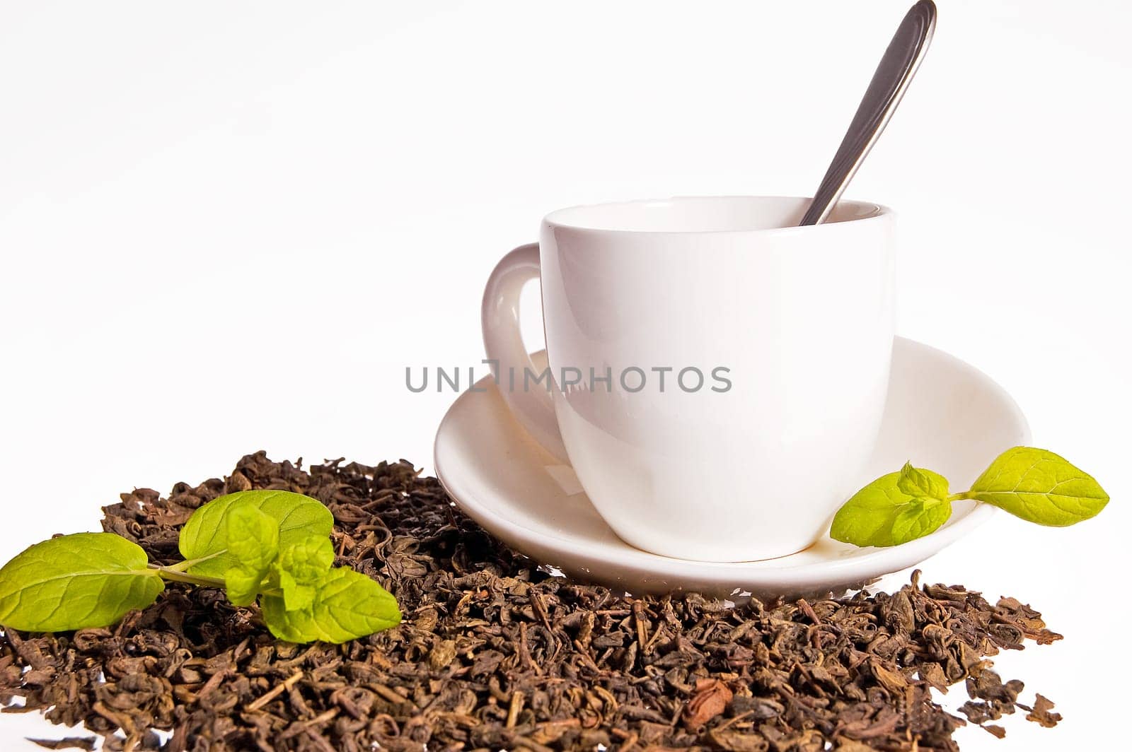 Green tea leaves and a cup of brewed tea with mint leaves