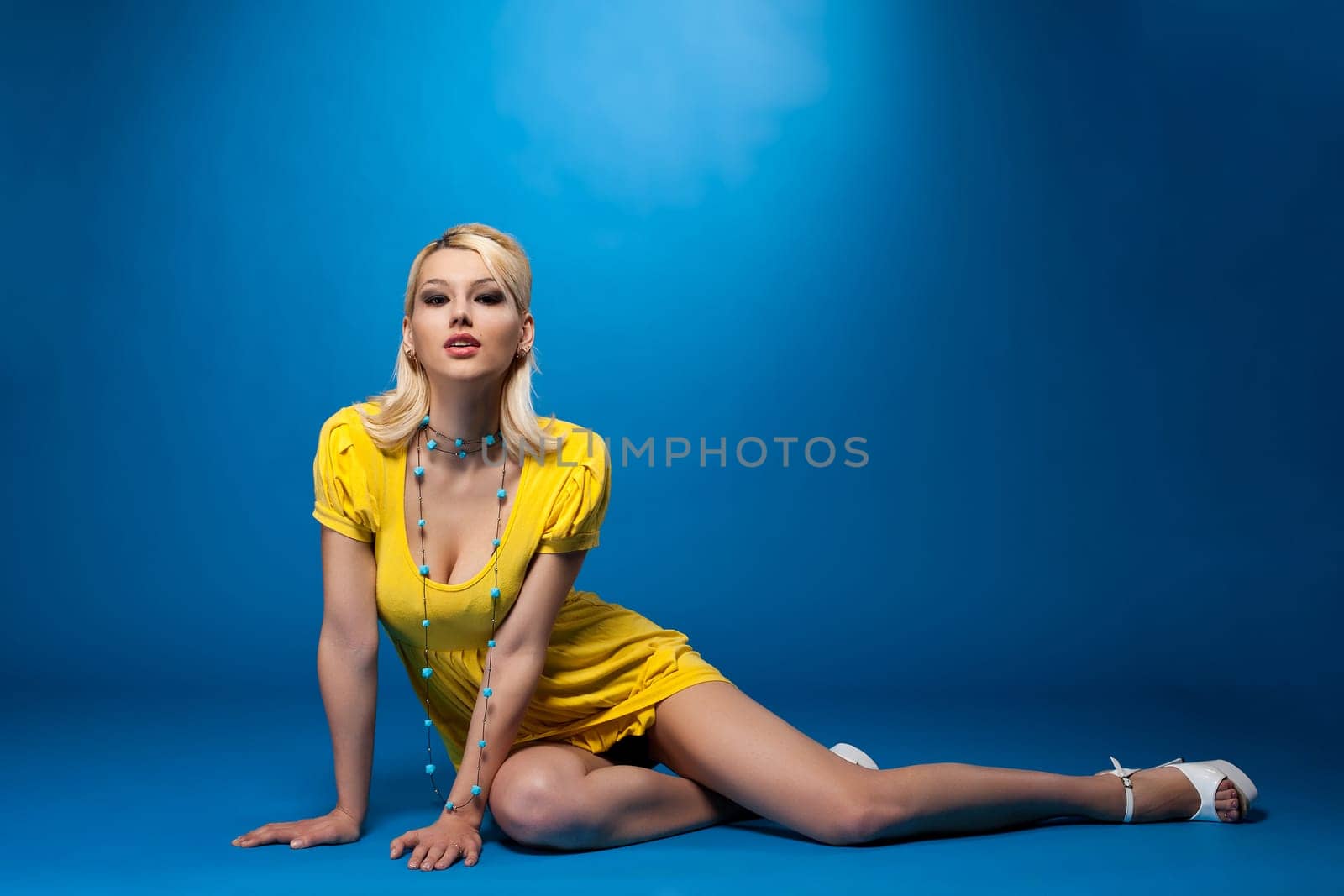 Beauty pinup woman in sexy yellow cloth lay on blue background
