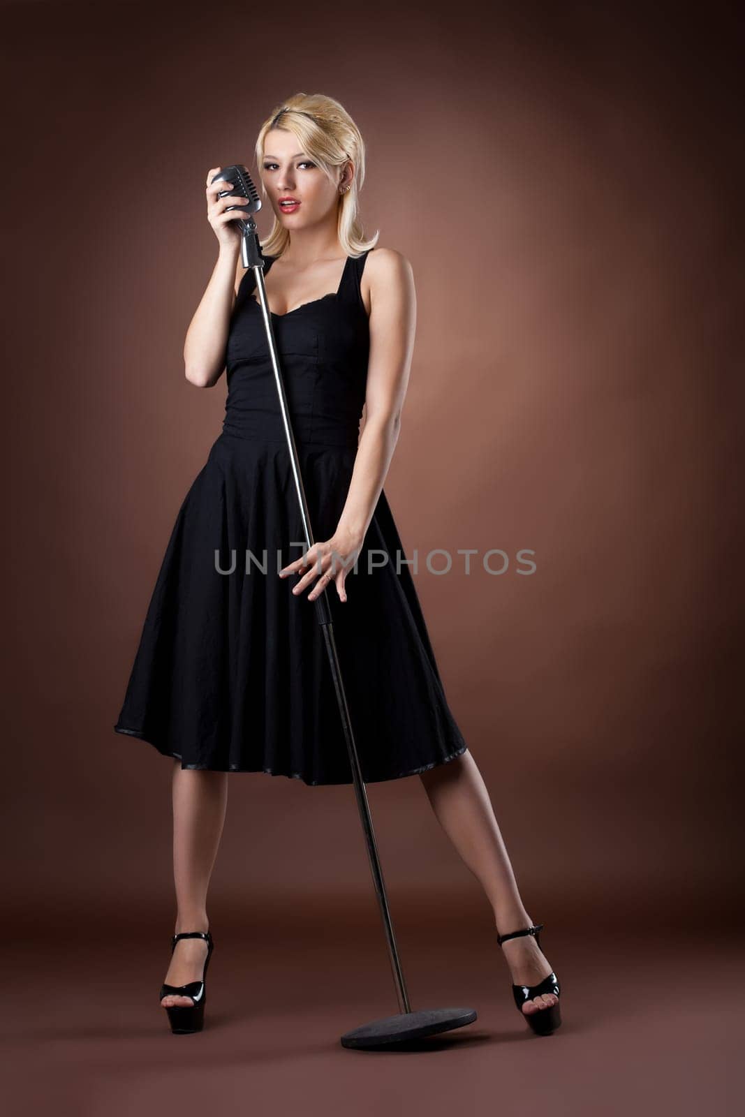 Beauty singer - woman pin-up portrait in black with microphone