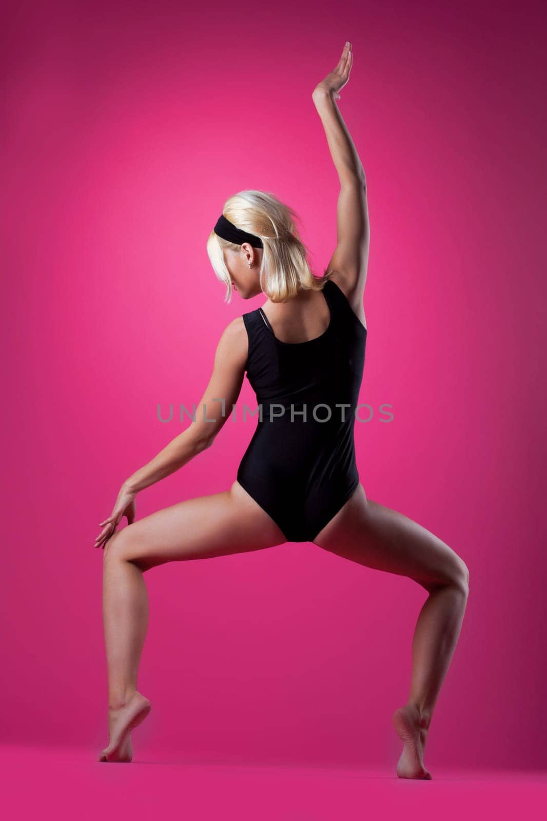 sexy blond woman in black swim suit on pink background