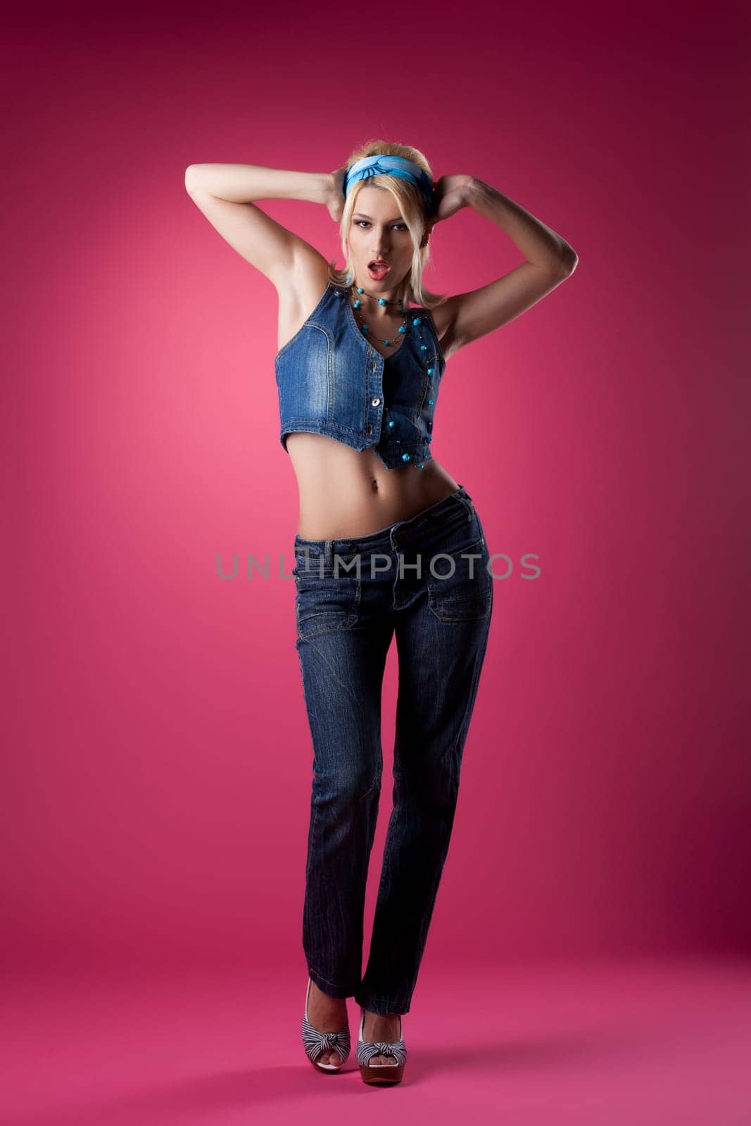 Tall sexy girl posing in jeans on pink background