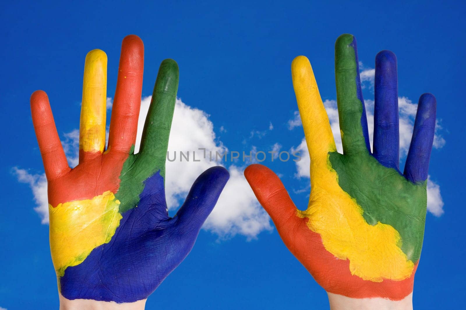 color painted hands on blue sky background