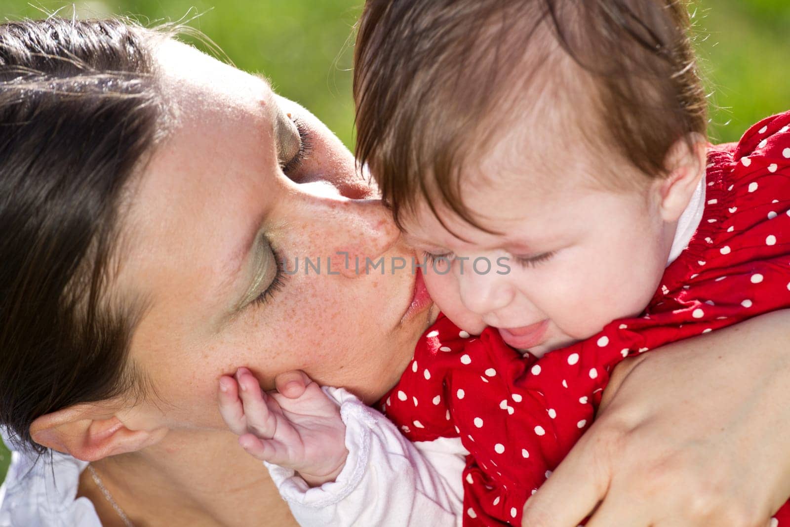 mother kissing baby in the park