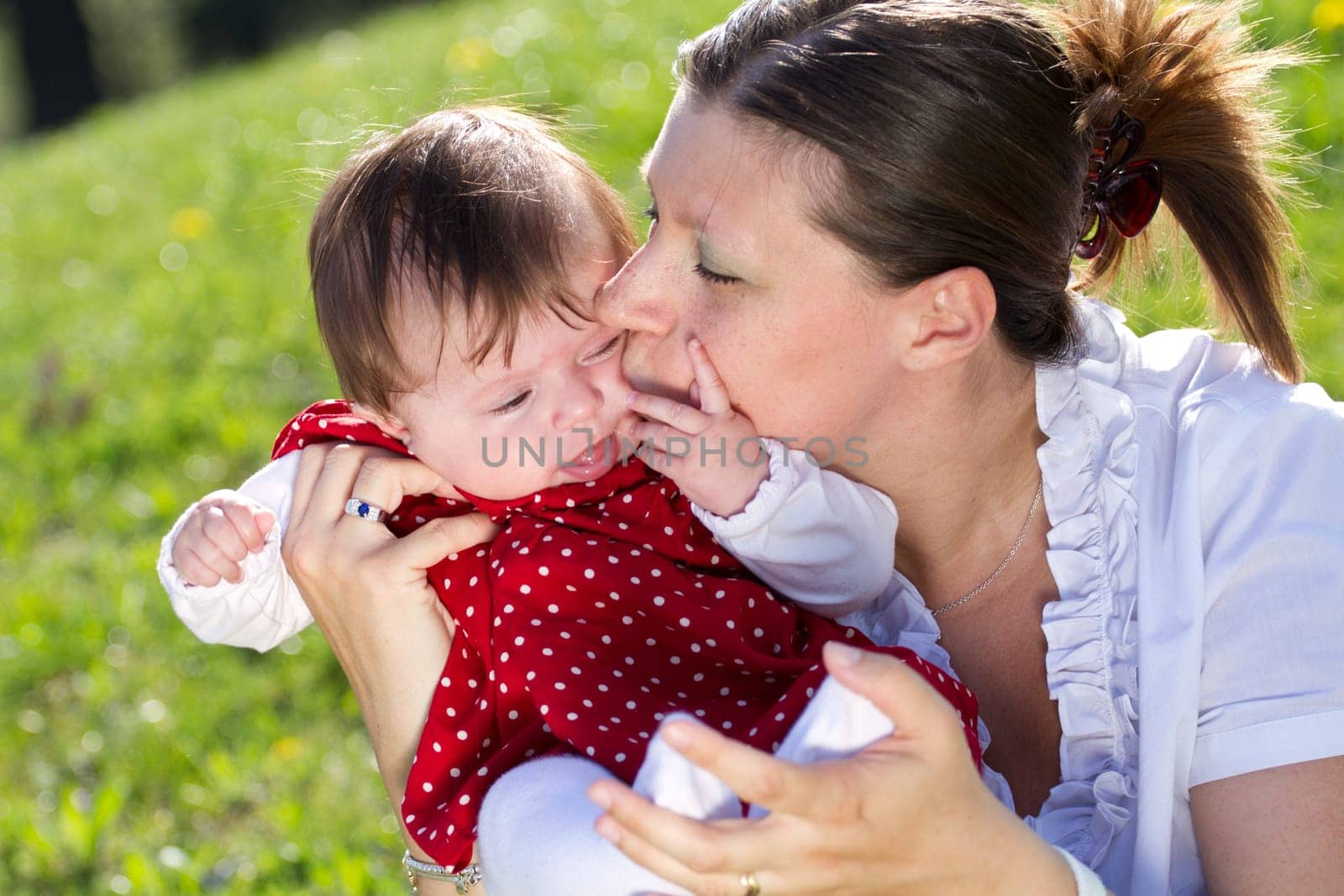 mother kissing baby in the park