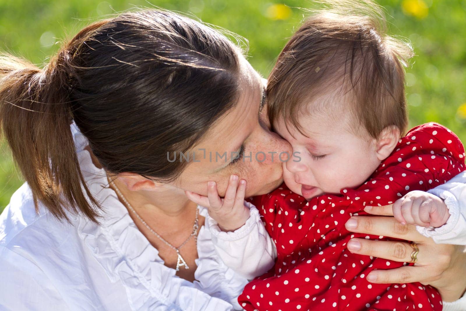 mother kissing baby in the park
