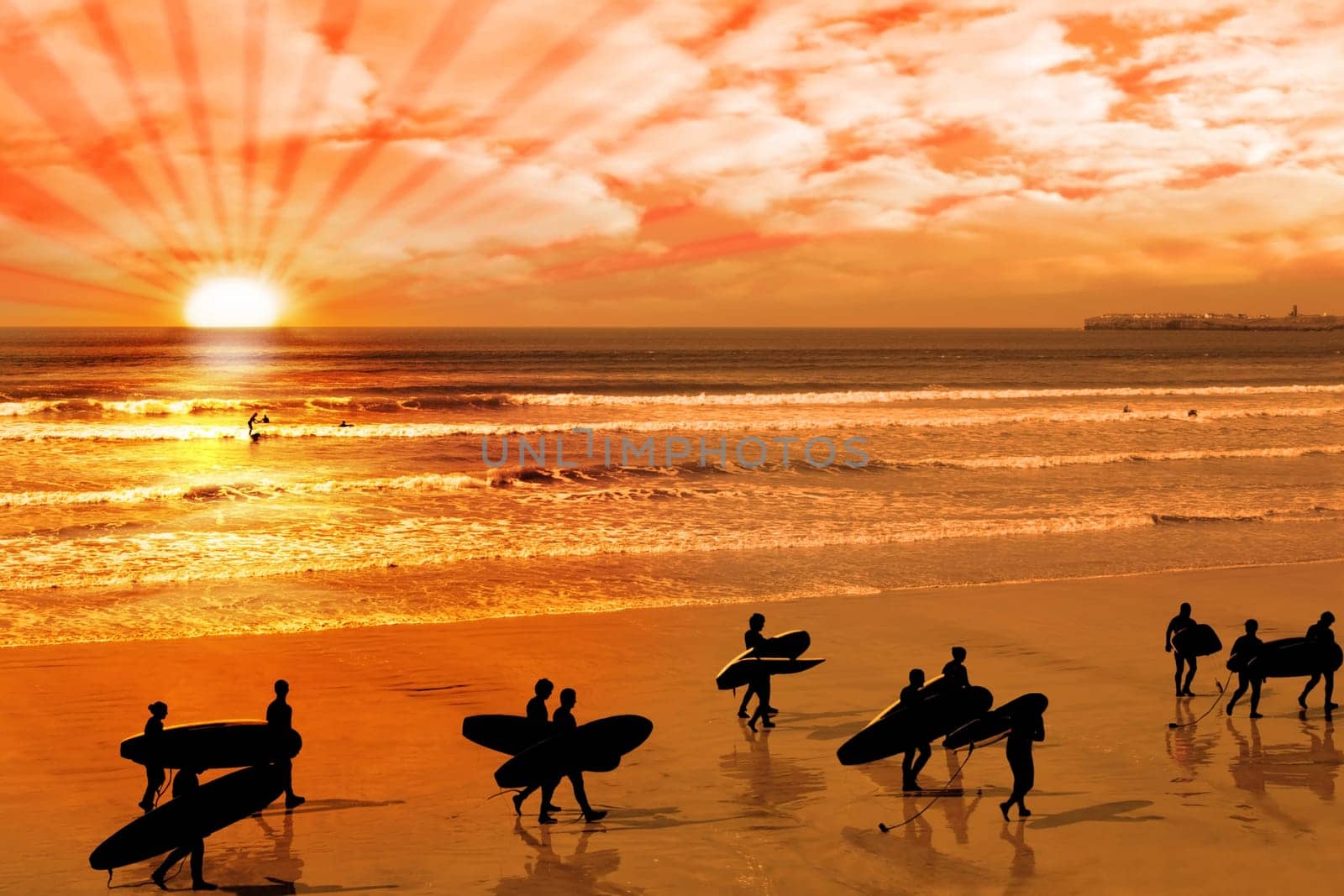 surfers walking on the beach in lahinch county clare ireland as the sun goes down