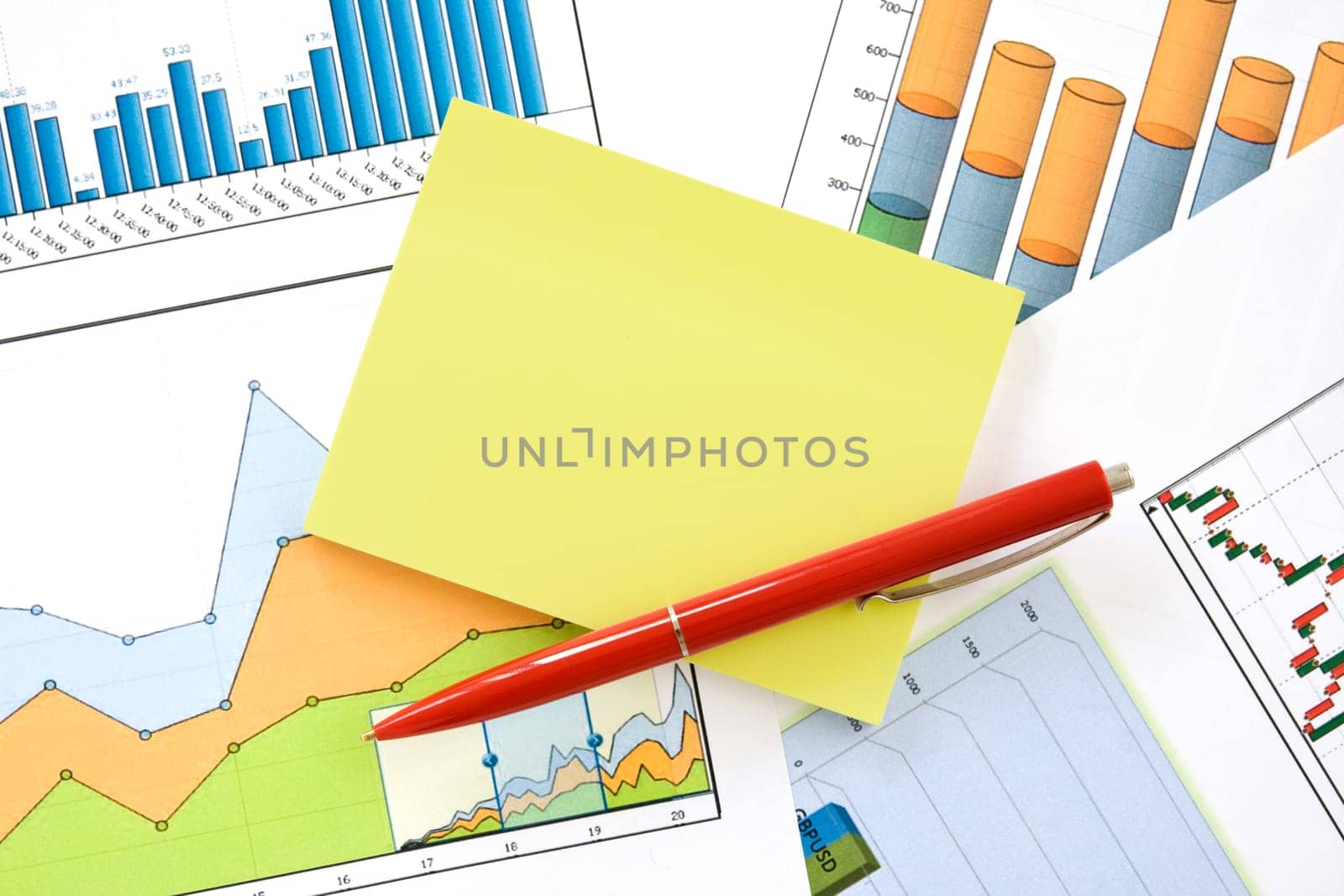red pen and yellow memo over financial charts