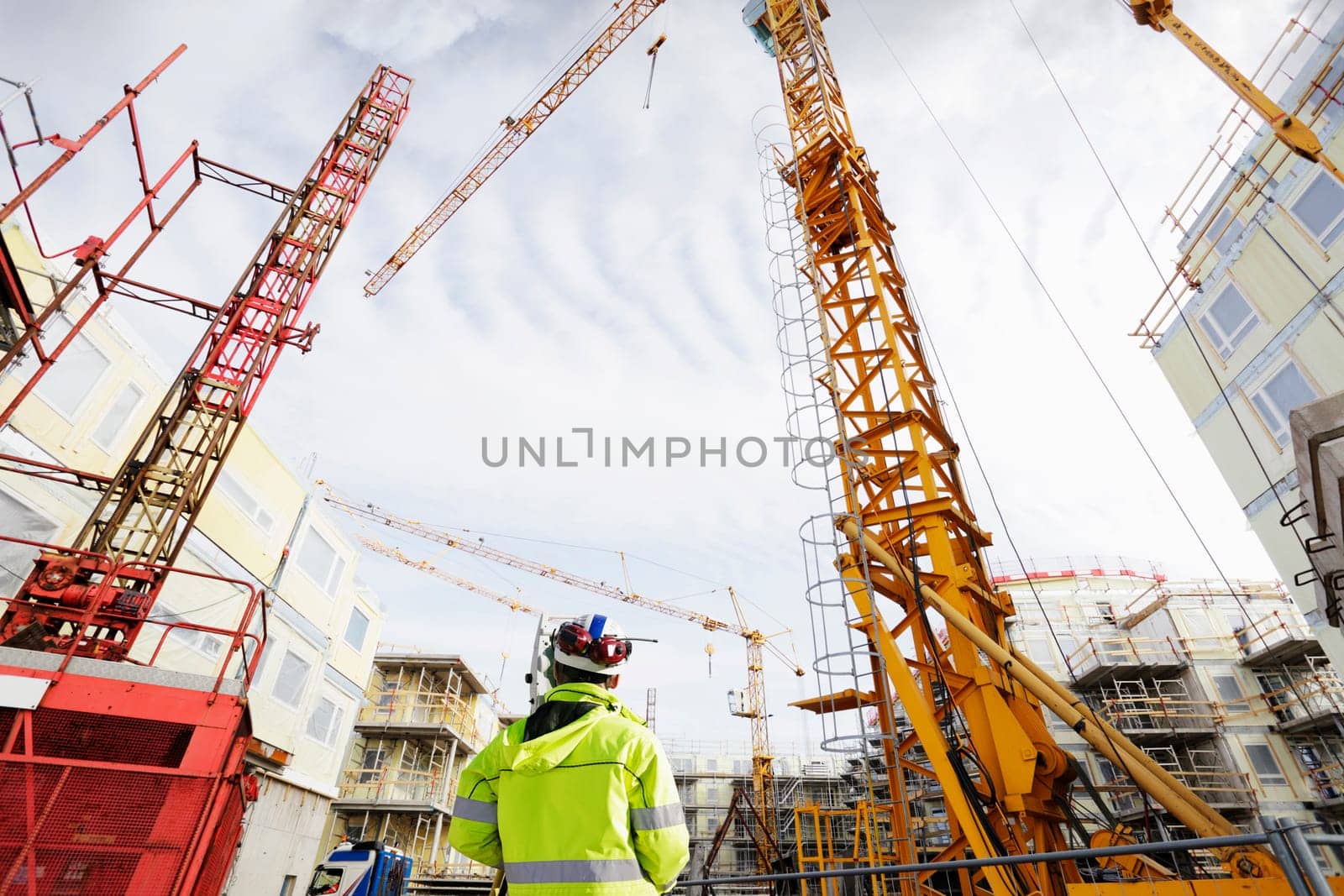 geodetist with geodesy measuring instrument, giant building site, wide angle view