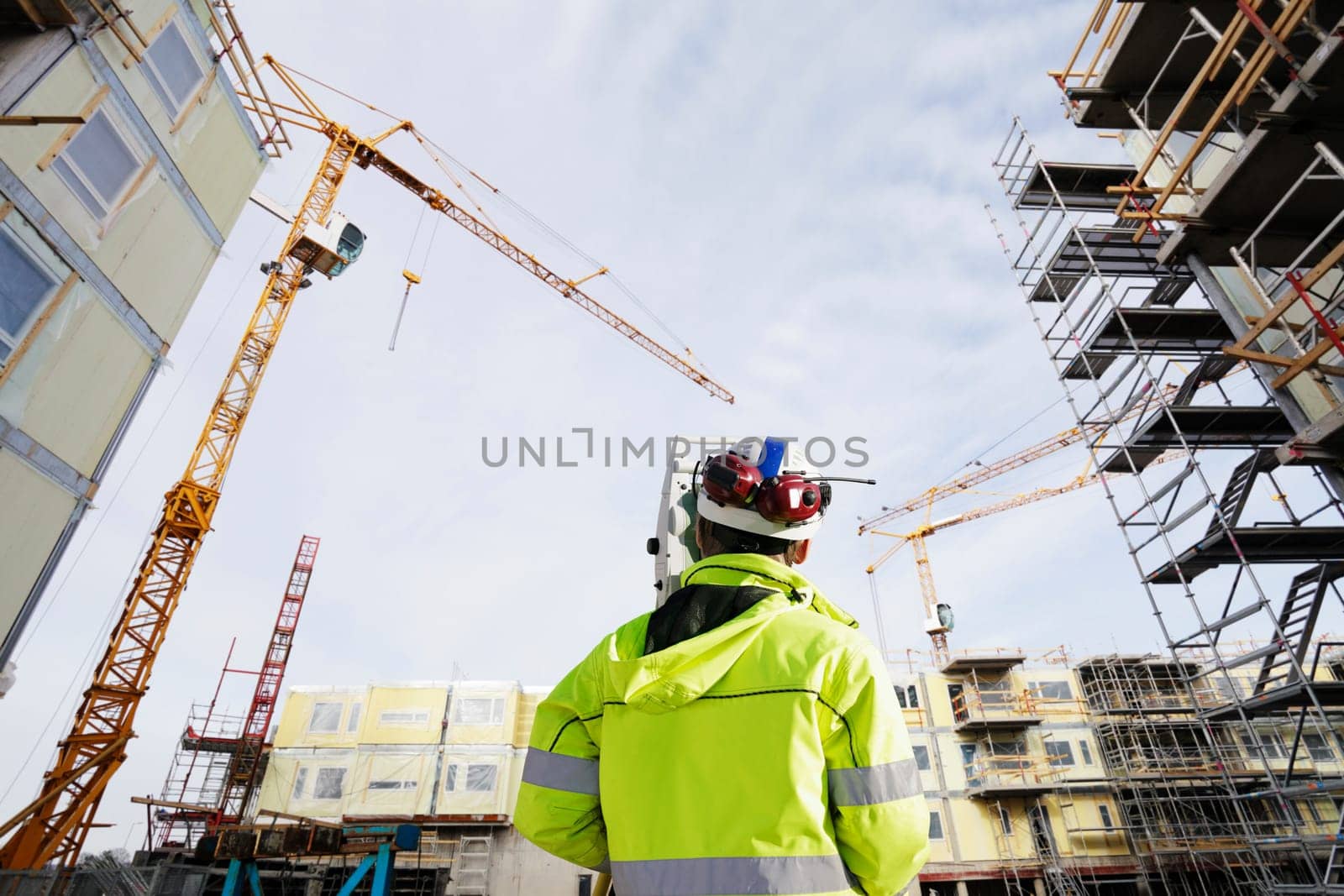 geodetist with measuring instrument, working inside large construction-site