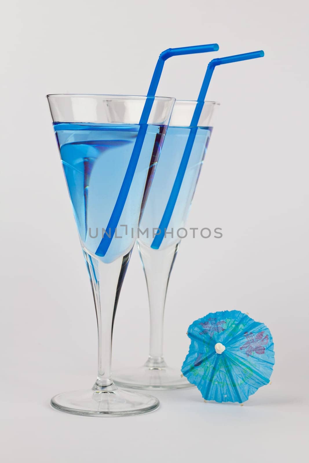 Two Blue Cocktails with blue straws and a blue umbrella