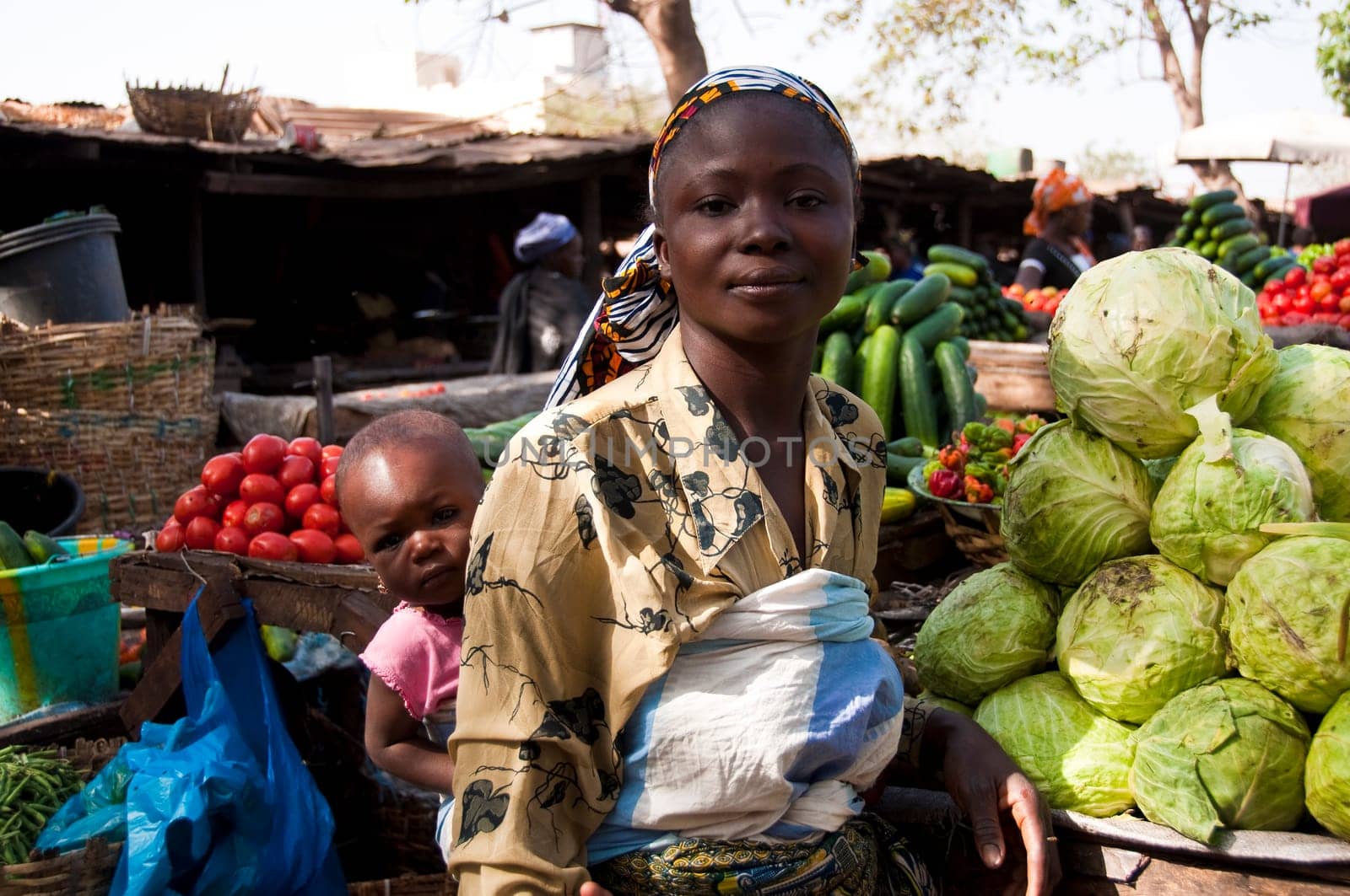 Young mother with her daughter selling vegetables on a market in Bamako, Mali, Africa