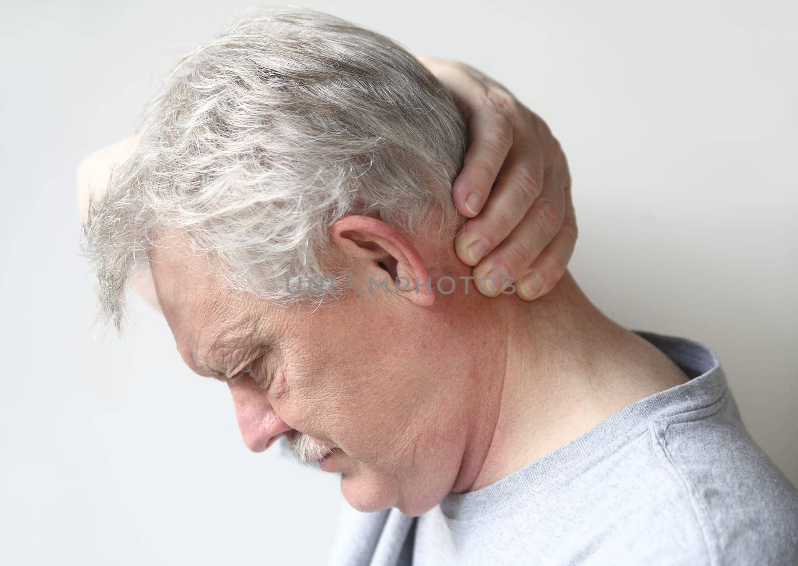 senior man with a hand at the back of his head
