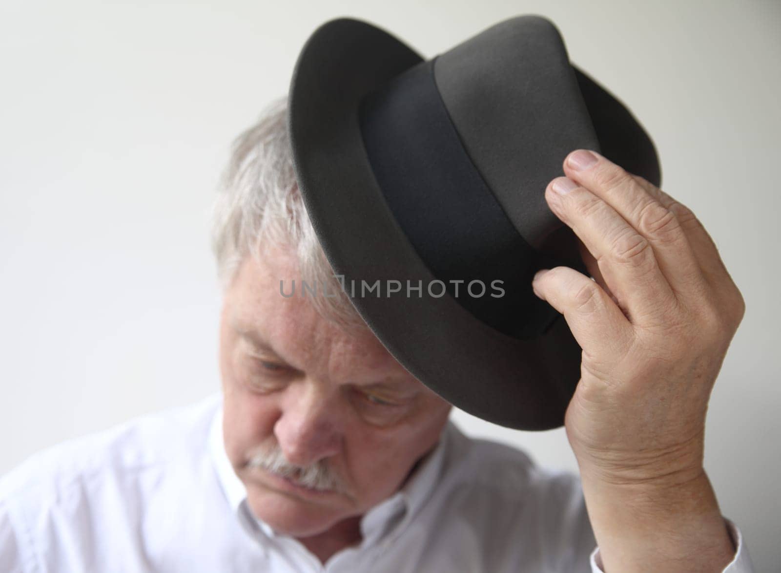 an older man puts on a fedora