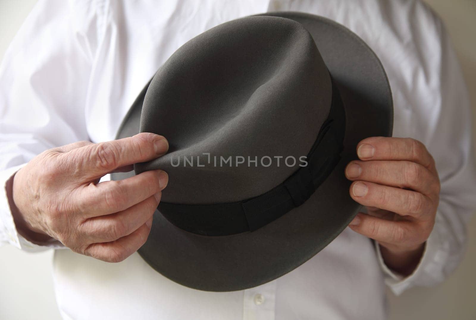 man holds a gray fedora