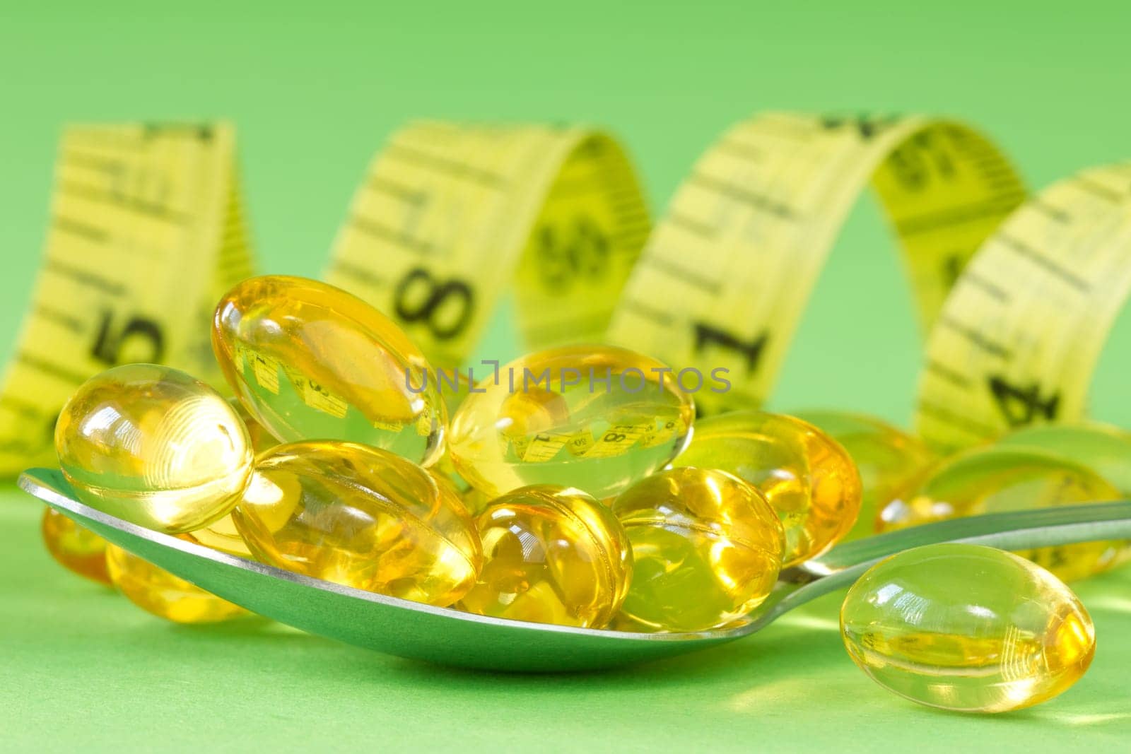 healthcare and medicine. measurement tape and spoon with pills on green background