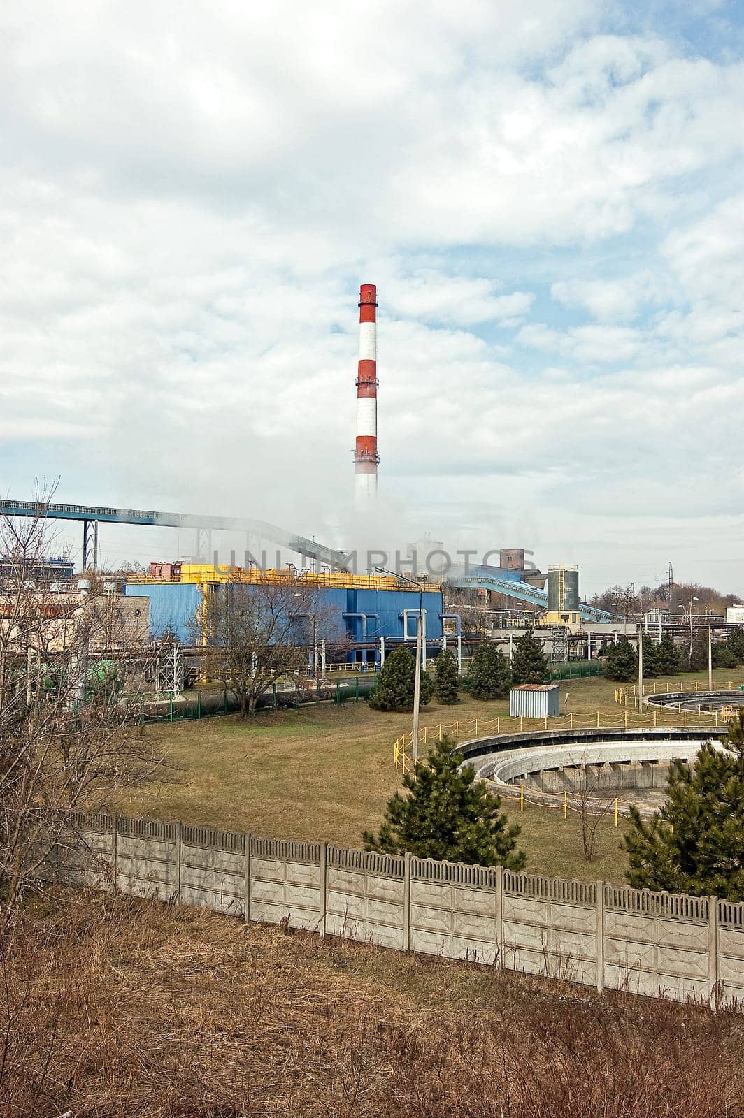 With a smoking chimney power plant on a sunny day