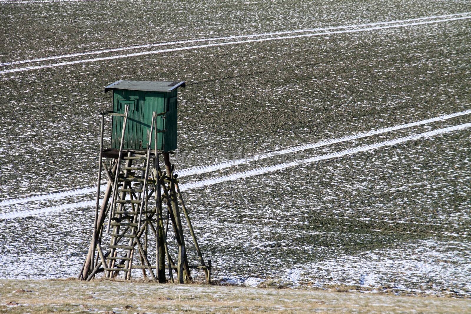 Field with snow tracks and high seat
