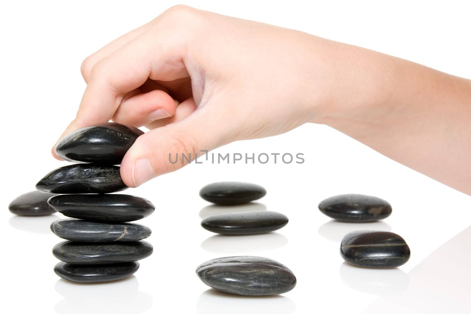 Building a Zen garden. hand and stones on white background.
