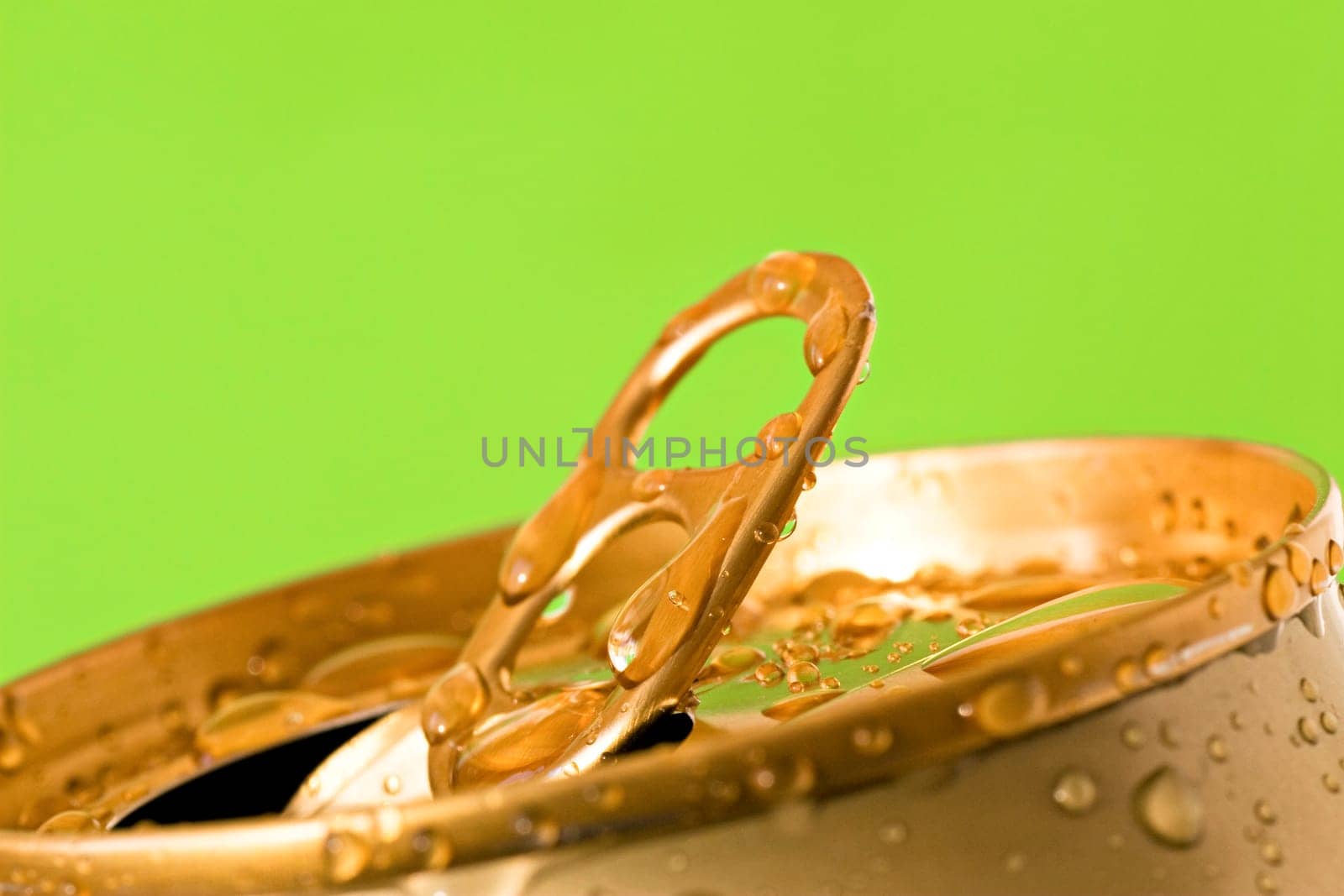 opened can of cold beer on green background
