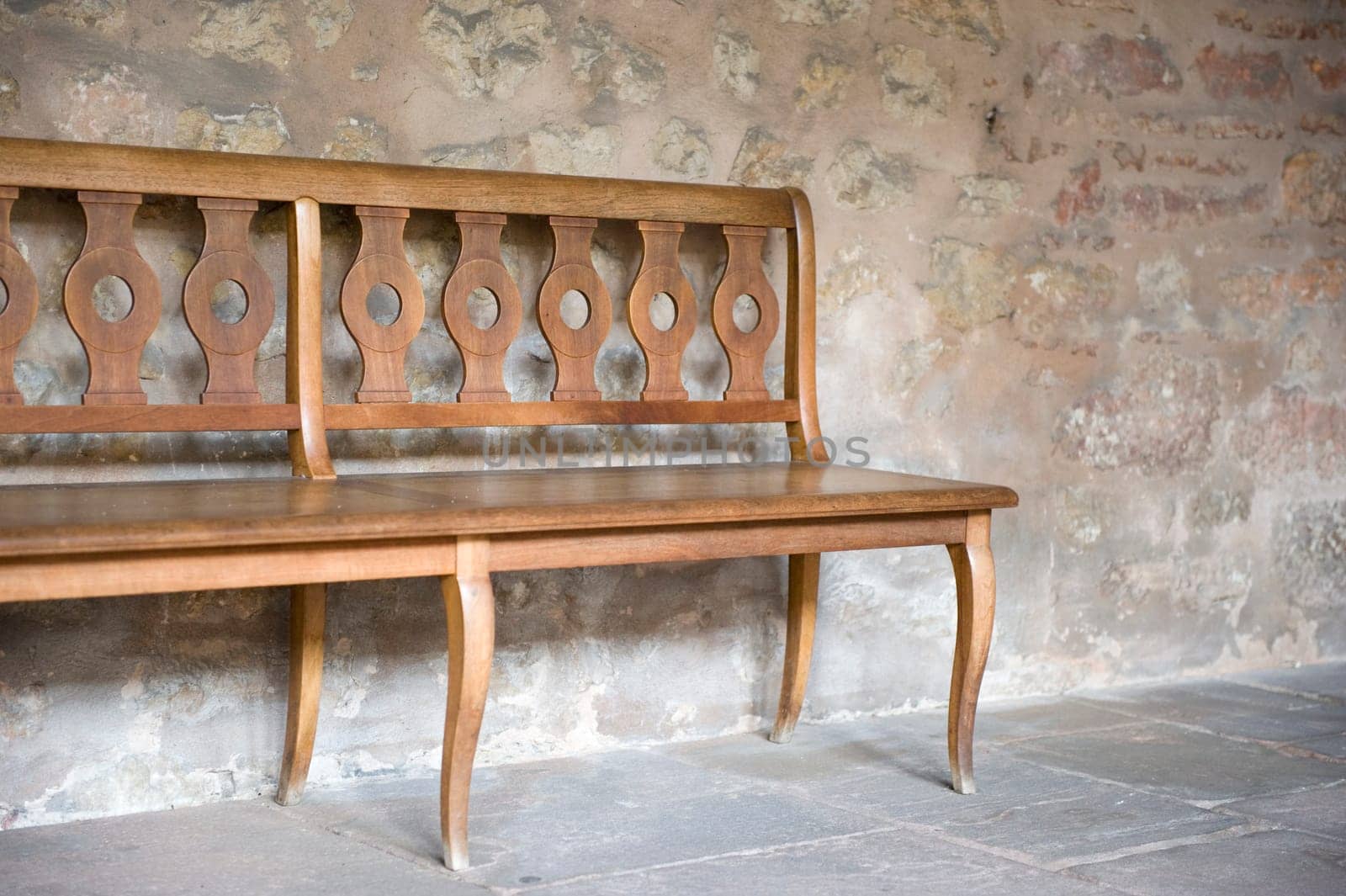 Wooden bench in front of stone wall