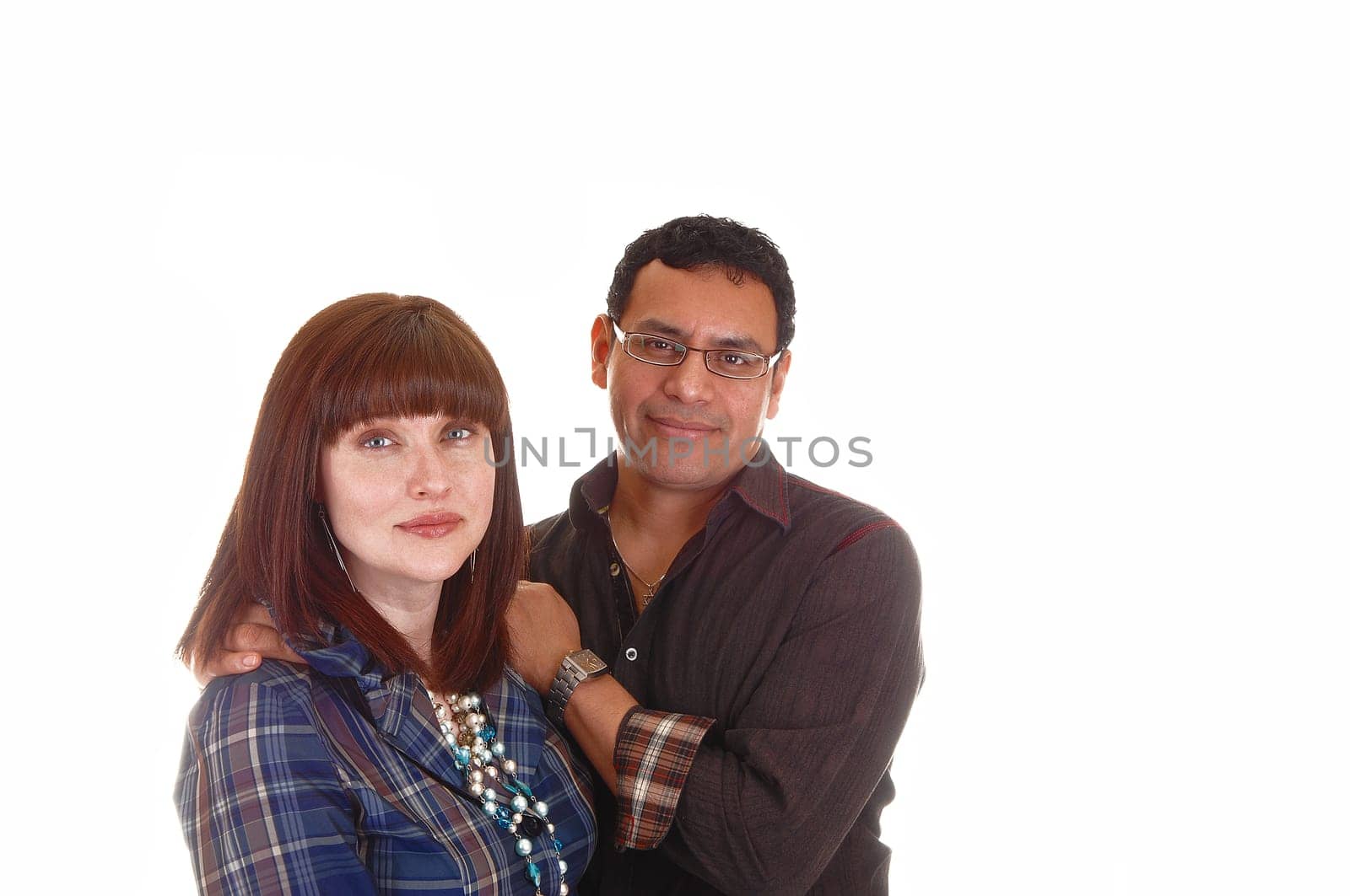 A closeup shoot of a mixed couple, Hispanic and Caucasian, she with red hair, blue shirt and necklace, standing for white background.