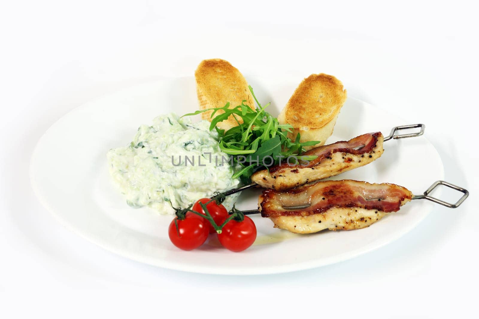 Greek food - tzatziki, chicken souvlaki with bacon and baguette on white background