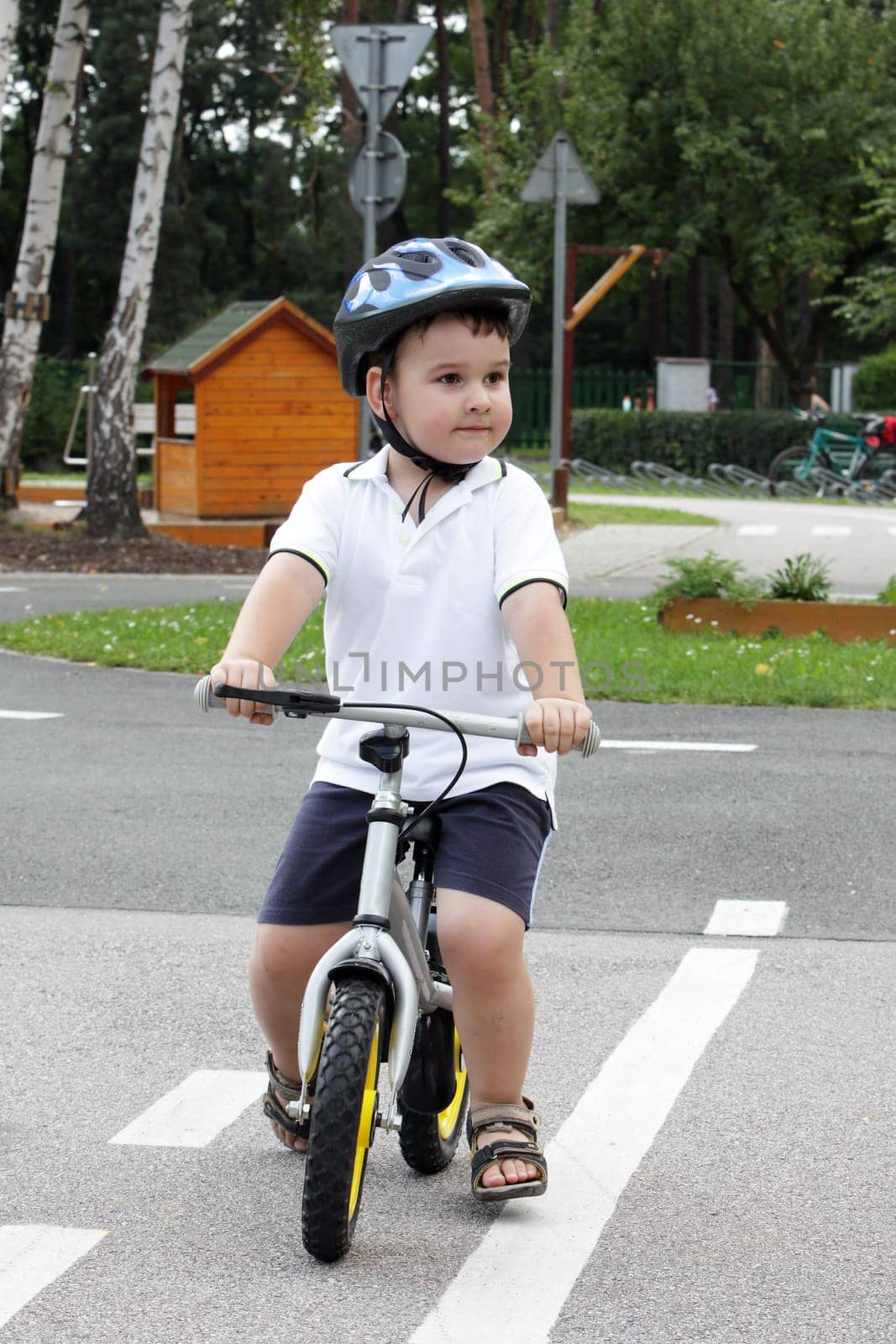 Baby boy on traffic playground for childs with crash helmet