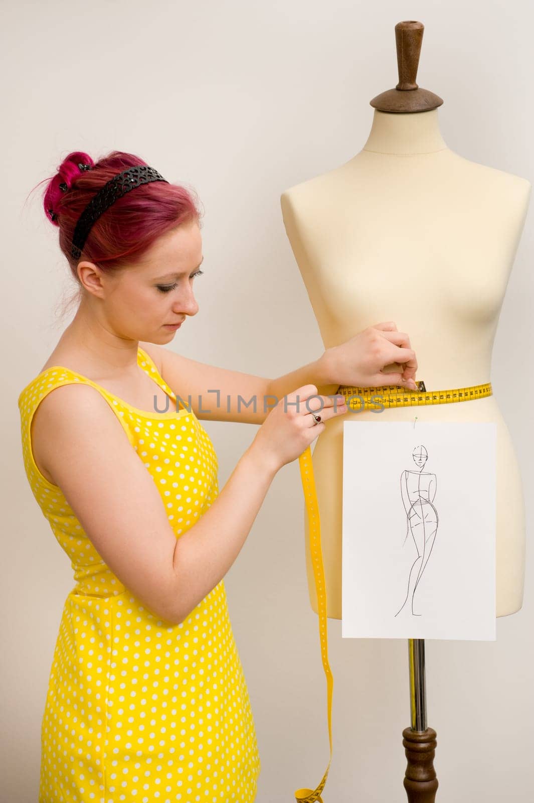 The young seamstress takes measurements of a group of tailors