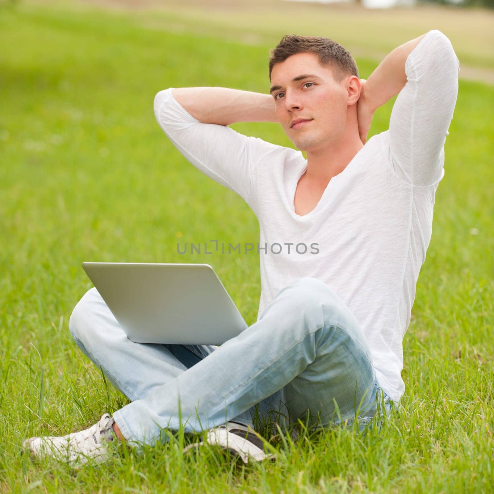 Young man with computer in a meadow
