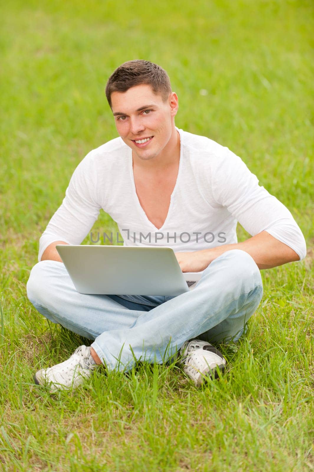 Young man with computer in a meadow