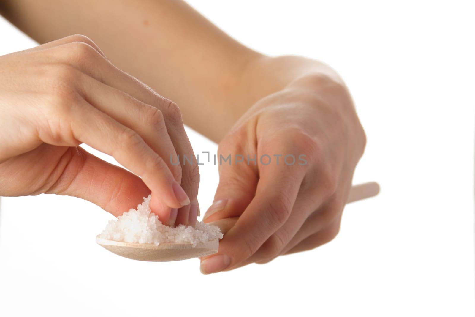 Female hands taking salt from a wooden wooden spoon