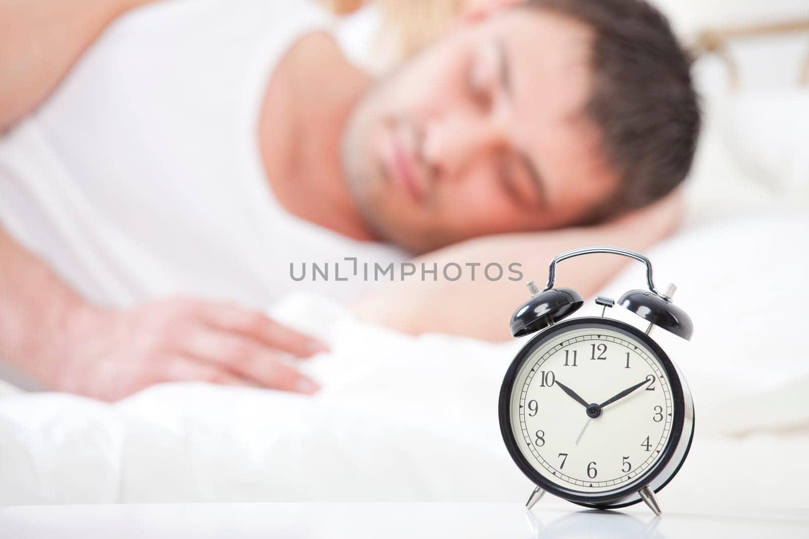 Man sleeping with alarm clock in foreground