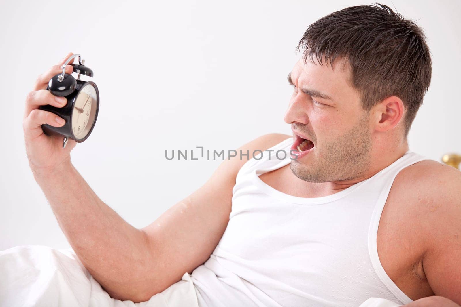 frustrated man in bed with alarm clock