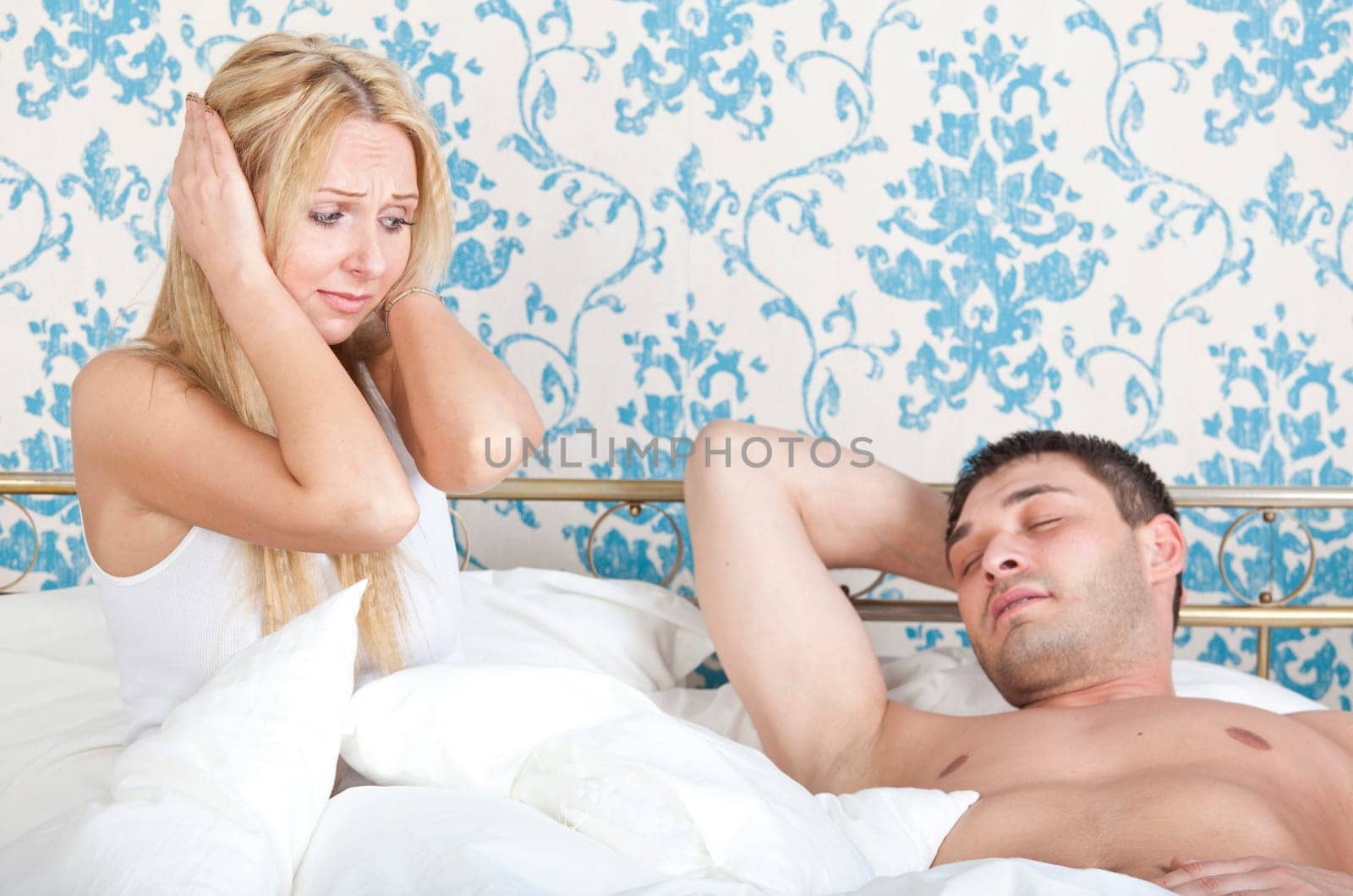 frustrated woman on the bed and snoring man sleeping