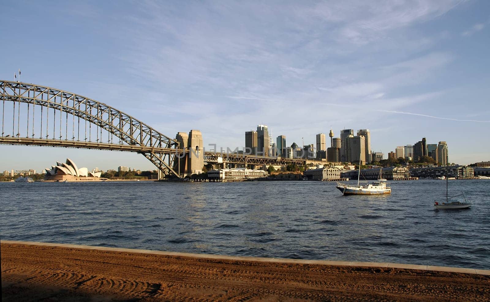 sydney view, opera house, harbour bridge and sydney tower visible, looks a little bit like rusty buildings because of the late afternoon light