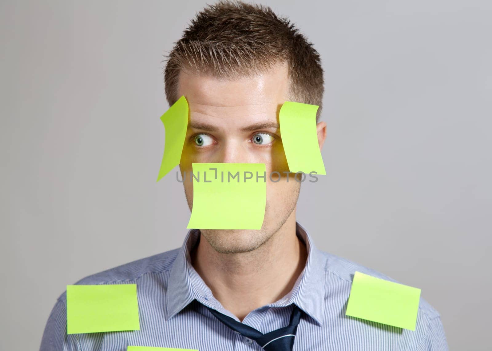 Confused businessman with post it notes on face and clothes