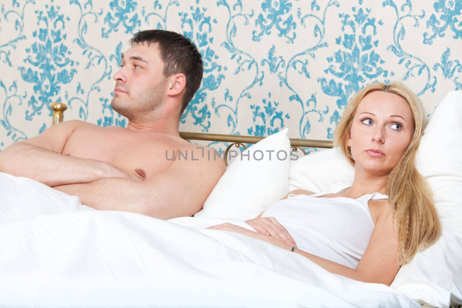 sad and unhappy couple lying in bed
