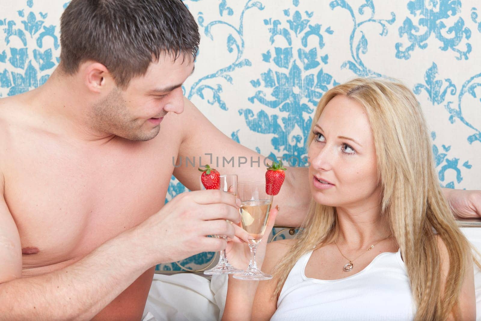 Young couple drinking sparkling wine in bed