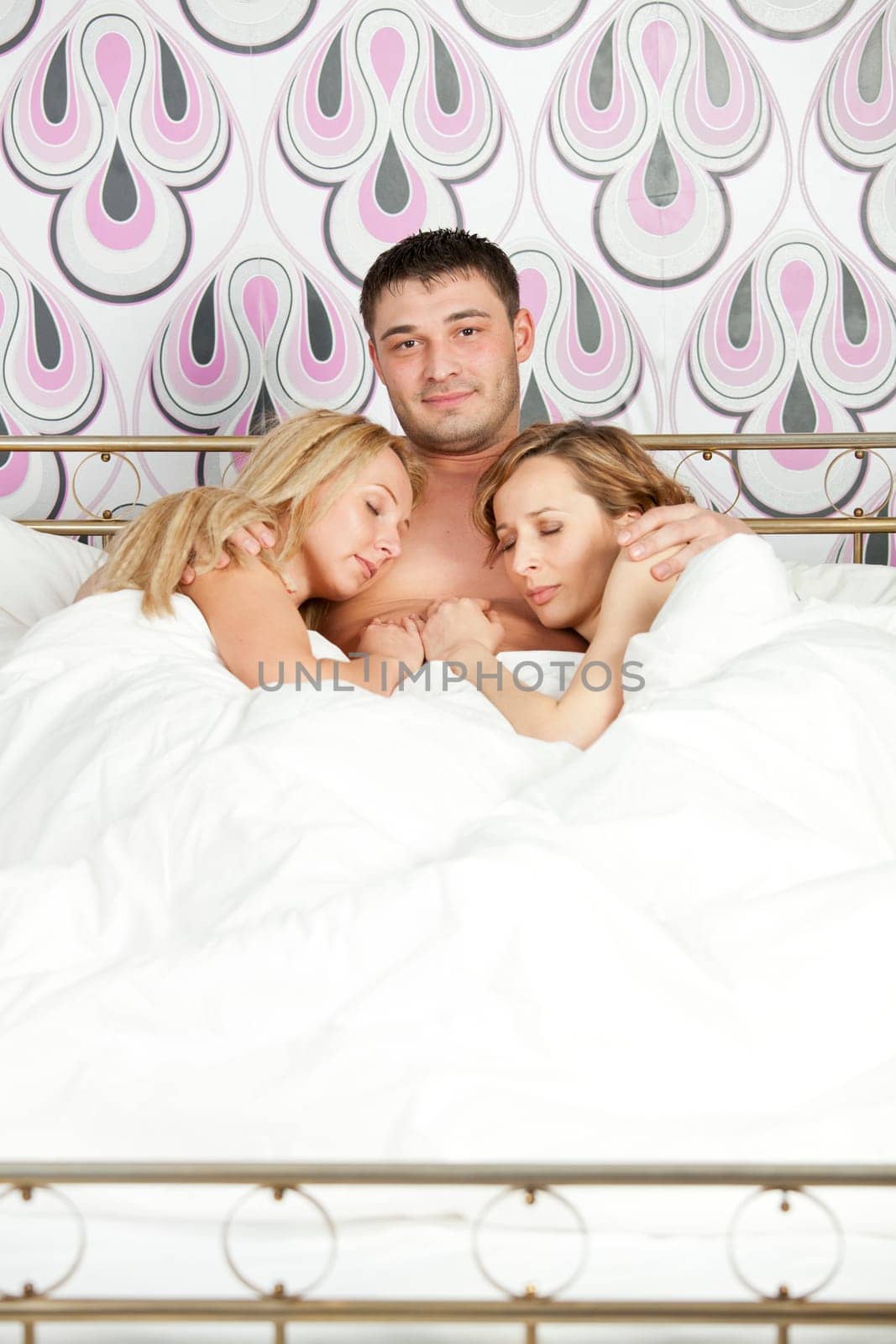 happy man lying with two women in bed